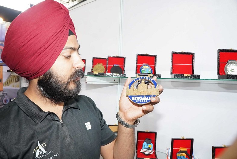 AN EXHIBITOR IS SEEN SHOWING DIFFERENT MEDAL DESIGNS AND TROPIES ON DISPLAY AT SPORTS EXPO AT HITEX